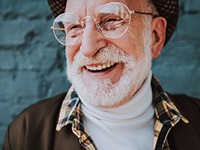 Man with dentures smiling wide on blue brick background