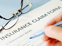 Person using pen to fill out insurance claim form