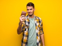 Man standing against yellow background, holding his wallet