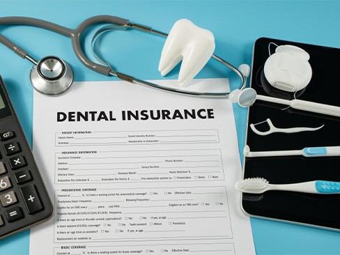 A dental insurance form next to dental tools