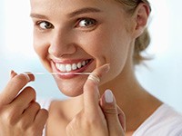 Woman smiling while flossing her teeth