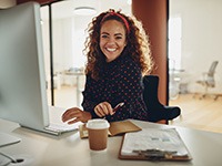 Woman smiling while working on laptop in office