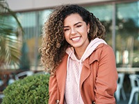 Woman with straight teeth smiling outside