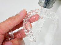 Closeup of patient rinsing clear aligners