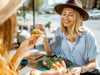 Two friends smiling while eating lunch outside