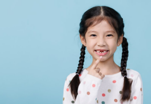 Little girl pointing at her missing teeth